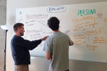 Zwei Männer blicken auf ein Whiteboard und diskutieren