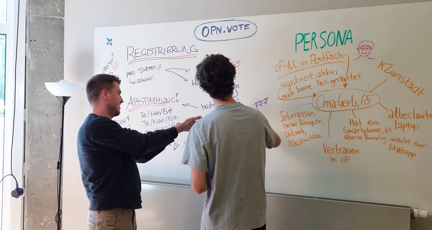 Zwei Männer blicken auf ein Whiteboard und diskutieren